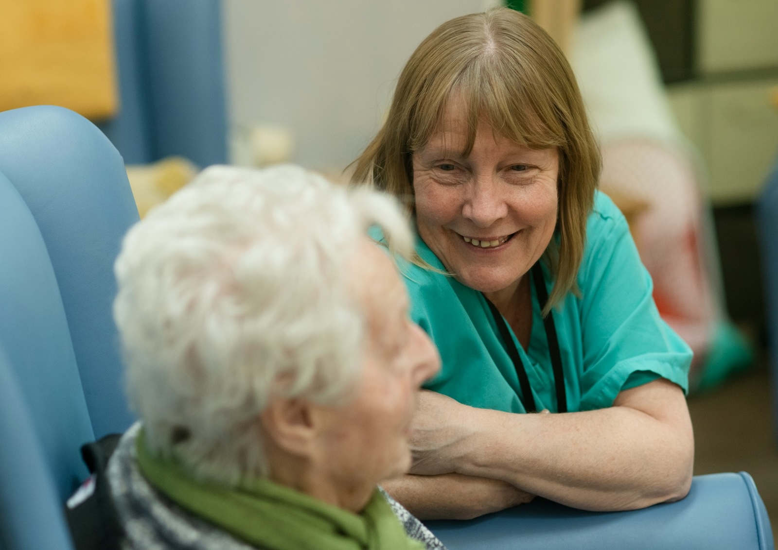 Care worker talking to an elderly patient in a hospital.